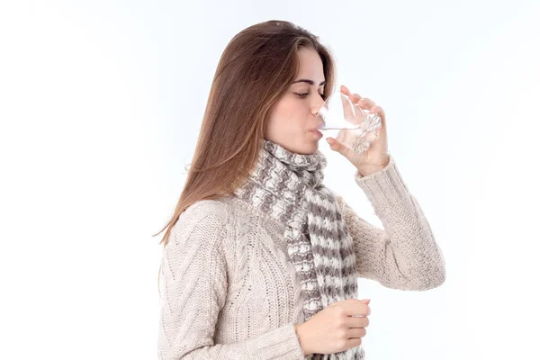 Flicka i tröja och varm halsduk dricker glas vatten isolerad på vit bakgrund — Stockfoto