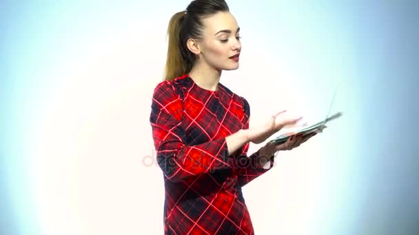 Красива жінка в елегантній червоній сукні з візерунком кидає гроші в повітря в студії — стокове відео