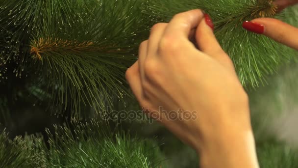 Mädchen schmückt den Weihnachtsbaum und hängt an einem Ast die blau glänzende Kugel — Stockvideo