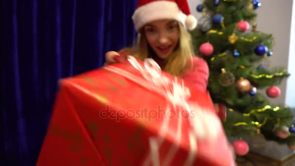 Happy young woman in santa hat dancing with christmas gift in hands — Stock Video