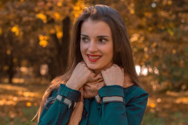 kırmızı ruj ile güzel kız gülümseyerek uzakta görünüyor ve eller eşarp tutar