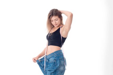 İnce genç kız el saç tutar ve beyaz arka plan üzerinde izole geniş pantolon bakar