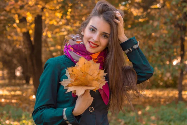 Hermosa chica con el pelo largo sosteniendo ramo de hojas en su mano y sonrisas — Foto de Stock