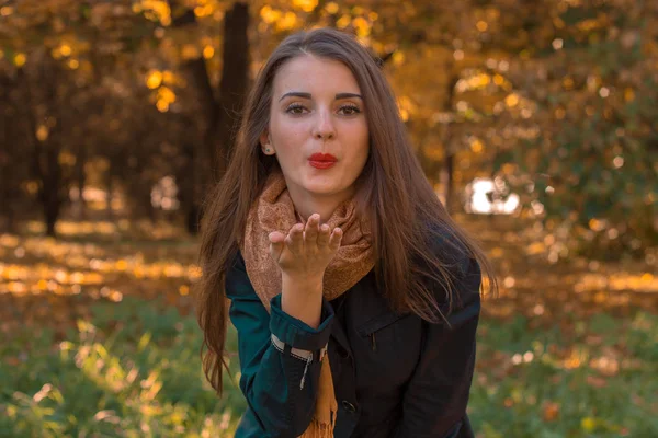 Giovane ragazza con le labbra rosse che invia un bacio nel parco — Foto Stock