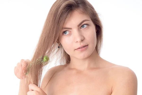 Jovencita mira hacia otro lado y se peina el pelo aislado sobre fondo blanco — Foto de Stock