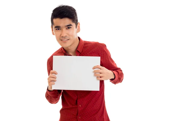 Jovem alegre em camisa vermelha com cartaz vazio em mãos posando isolado no fundo branco — Fotografia de Stock