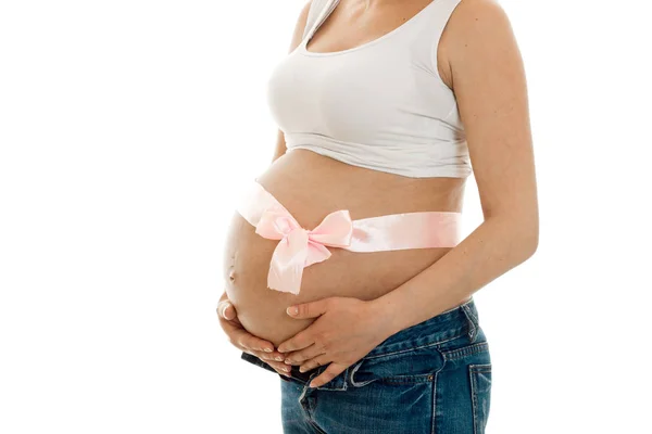 Embarazada con cinta rosa en su gran vientre posando aislado sobre fondo blanco — Foto de Stock