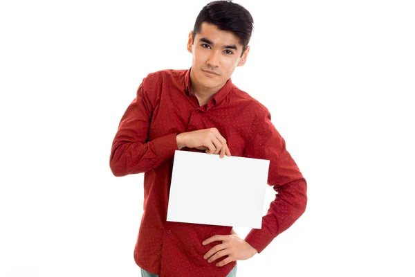 Bonito jovem cara no vermelho camisa com vazio cartaz no mãos posando isolado no branco fundo — Fotografia de Stock