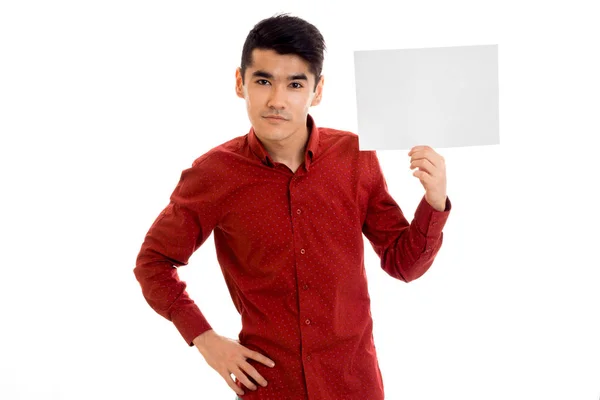 Elegante giovane ragazzo in camicia rossa con cartello vuoto in posa mani isolate su sfondo bianco — Foto Stock