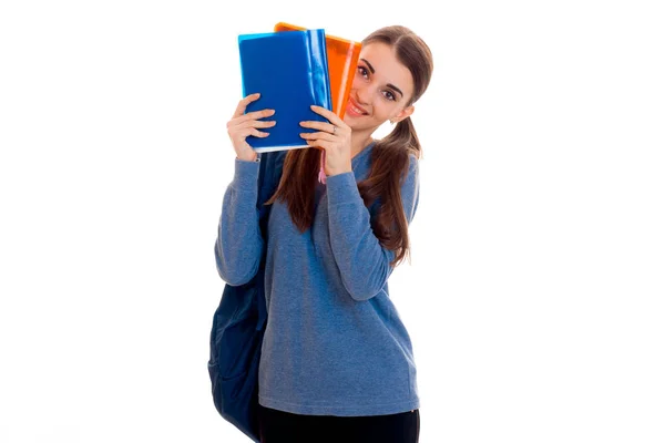 Nettes junges Studentmädchen mit Rucksack und Ordnern für Notizbücher in ihren Händen, die in die Kamera schauen und isoliert auf weißem Hintergrund lächeln — Stockfoto