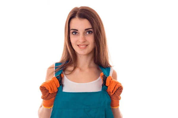 Attraente bruna donna costruttore rende rinnovamento e sorridente sulla macchina fotografica in uniforme isolato su sfondo bianco — Foto Stock