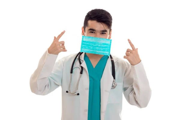 Médico masculino en uniforme y máscara con estetoscopio posando aislado sobre fondo blanco —  Fotos de Stock