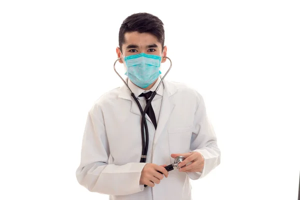 Giovane medico maschio in uniforme e maschera con stetoscopio guardando la fotocamera isolata su sfondo bianco — Foto Stock