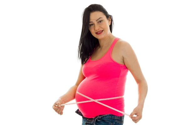 Feliz futura mãe grávida na camisa rosa medir sua barriga isolada no fundo branco — Fotografia de Stock