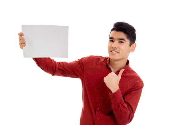 Elegância jovem em camiseta vermelha com cartaz vazio olhando para a câmera e mostrando polegares isolados no fundo branco — Fotografia de Stock