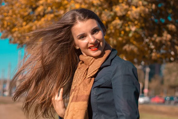 Bella ragazza sta nel parco al sole e i suoi capelli volano via con il vento — Foto Stock