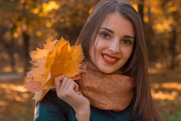 빨간 립스틱과 아름 다운 소녀 미소와 나뭇잎을 손에 계속 클로즈업 — 스톡 사진