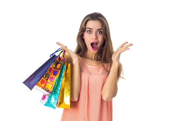 Joven con gran sorpresa sostiene en su mano una gran cantidad de bolsas de colores de tiendas aisladas sobre fondo blanco — Foto de Stock