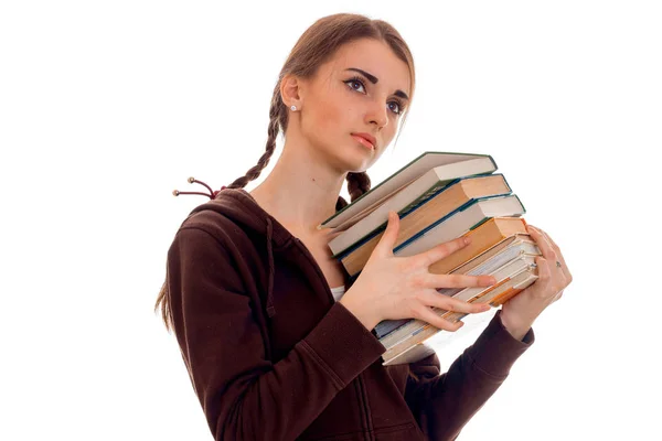 Fatigué jeune fille étudiante brune en vêtements de sport brun avec beaucoup de livres dans ses mains posant isolé sur fond blanc — Photo