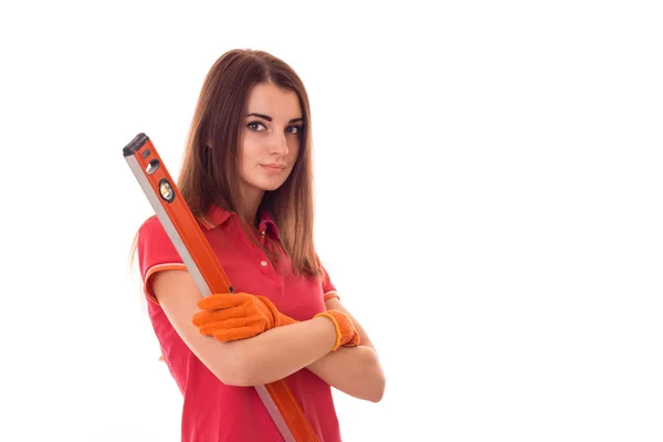 Atractiva chica joven constructora morena en uniforme hace renovación con herramientas en sus manos aisladas sobre fondo blanco — Foto de Stock