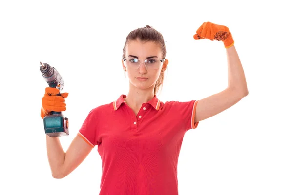 Красота юная брюнетка строитель девушка в форме и очках делает ремонт с дрелью в руках изолированы на белом фоне — стоковое фото