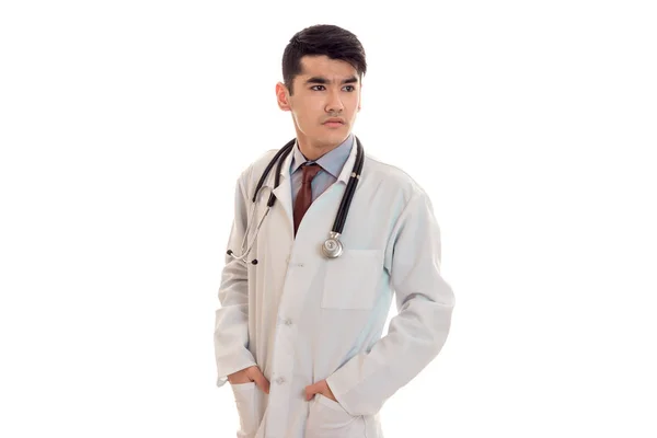 Joven médico morena elegante en uniforme con estetoscopio mirando hacia otro lado aislado sobre fondo blanco — Foto de Stock