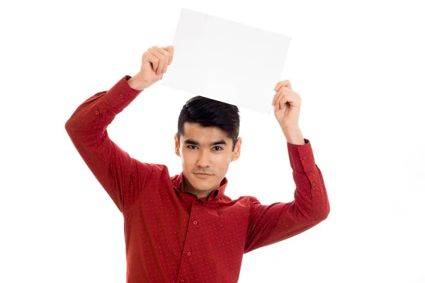 Jovem modelo masculino bonito em camisa vermelha com placard vazio em mãos isoladas no fundo branco — Fotografia de Stock