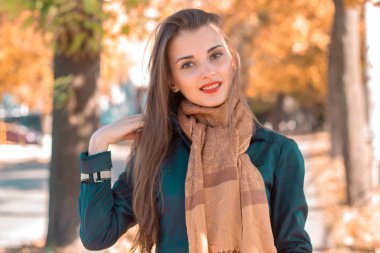 uzun bir eşarp doğrudan bakarak ve gülümseyen genç sevimli kız