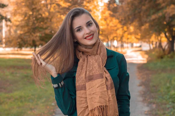 A vonzó lány áll az utcán a parkban és a mosoly — Stock Fotó