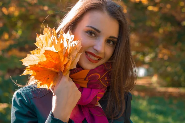 Retrato de una hermosa chica con lápiz labial rojo que mantiene las hojas en la mano, primer plano — Foto de Stock