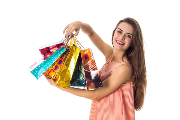 Joven chica disfruta y sostiene en su mano una hermosa bolsas de colores aislados sobre fondo blanco — Foto de Stock