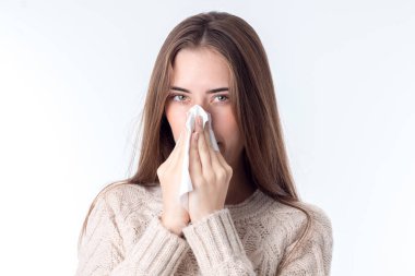 genç kız dik duruyor ve burun yakınındaki mendil tutan beyaz arka plan üzerinde izole