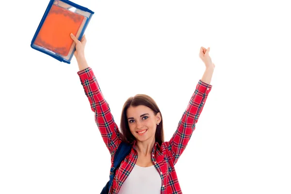 Glückliche junge brünette Studentin mit blauem Rucksack auf ihren Schultern und Ordner für Notizbücher in ihren Händen, die in die Kamera lächelt, isoliert auf weißem Hintergrund — Stockfoto