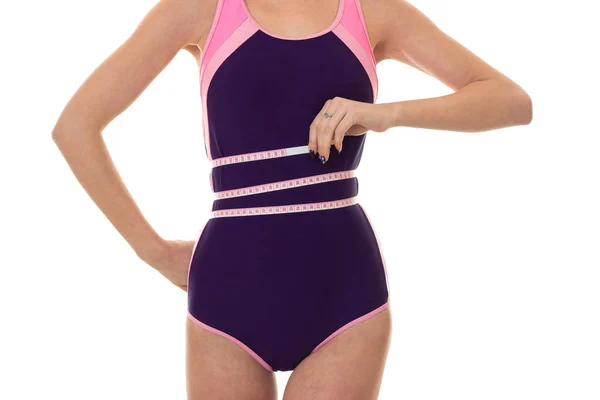 Slanke vrouw in lichaam zwembroek meten haar taille geïsoleerd op witte achtergrond — Stockfoto
