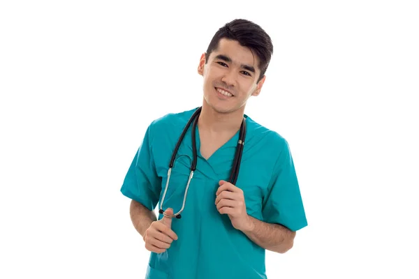 Jovem morena alegre médico homem em uniforme azul com estetoscópio posando isolado no fundo branco — Fotografia de Stock