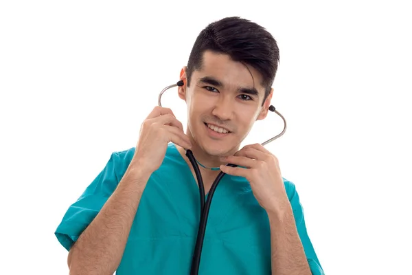 Retrato de jovem morena alegre médico homem em uniforme azul com estetoscópio posando isolado no fundo branco — Fotografia de Stock