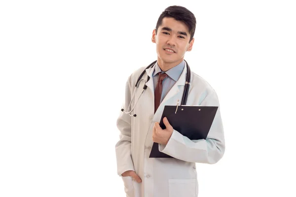 Hermosa joven morena hombre médico en uniforme blanco con estetoscopio mirando a la cámara aislada en el estudio — Foto de Stock