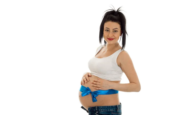 Sevimli genç esmer hamile kız beyaz arka plan üzerinde izole poz onun göbek üzerinde mavi bant ile — Stok fotoğraf