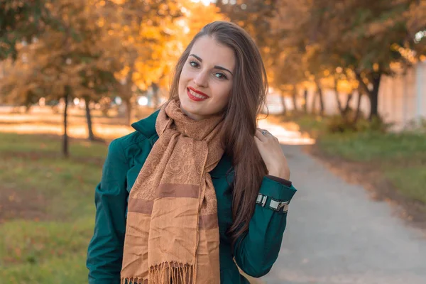 Lachende jonge vrouw in een lange bruine sjaal staat op straat — Stockfoto