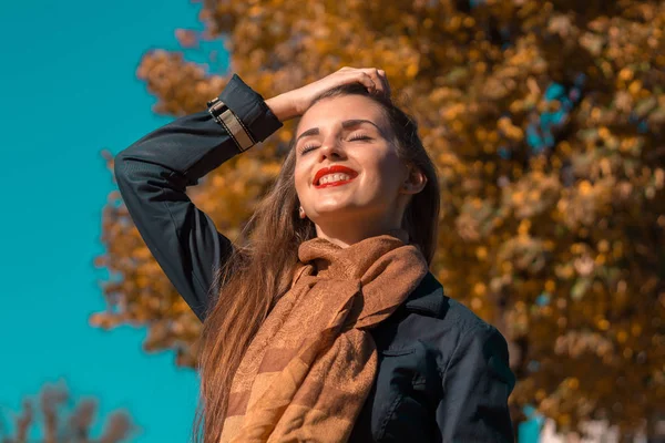 Belle fille dans l'écharpe garde les cheveux de la main fermer ses yeux et sourit — Photo