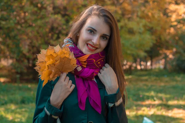 Χαριτωμένο νεαρή κοπέλα που κρατά τα φύλλα στο χέρι και χαμόγελα — Φωτογραφία Αρχείου