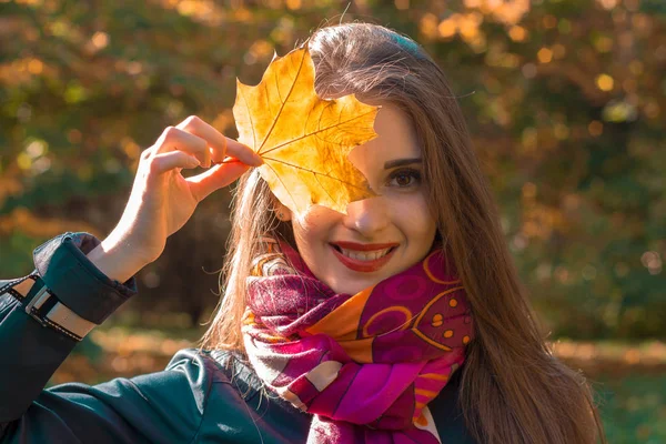 Portret van een mooi jong meisje die houdt van blad in de buurt van de ogen en glimlach close-up — Stockfoto