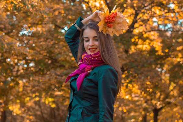 Sonriente joven levantó la mano con las hojas por encima de la cabeza y los ojos cerrados — Foto de Stock