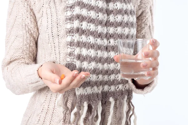 Flickan i tröjan håller innan ett piller och glas vatten närbild — Stockfoto