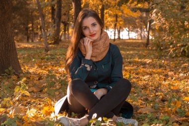 genç kız sonbahar Park yaprakları arasında oturan