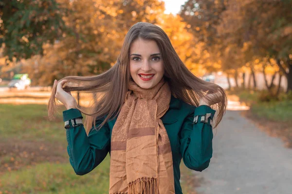 Linda chica ríe y mantiene las manos el pelo en el parque —  Fotos de Stock