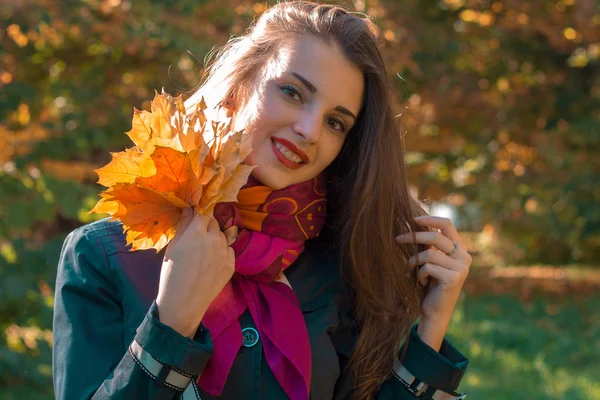 Piękna dziewczyna uśmiechając się, patrząc w przyszłość i utrzymuje zbliżenie liści — Zdjęcie stockowe