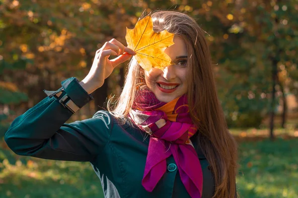 Jovem bonito menina está sorrindo e segurando uma folha perto do olho close-up — Fotografia de Stock