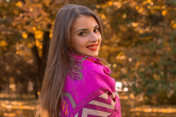 Menina bonita fica de lado em um grande lenço quente sobre os ombros e sorrisos — Fotografia de Stock