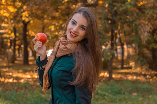 Bonito menina vale a pena virar de lado sorrisos e mantém a Apple no parque — Fotografia de Stock